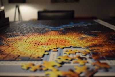 A cozy table scattered with colorful jigsaw puzzle pieces mid-assembly.
