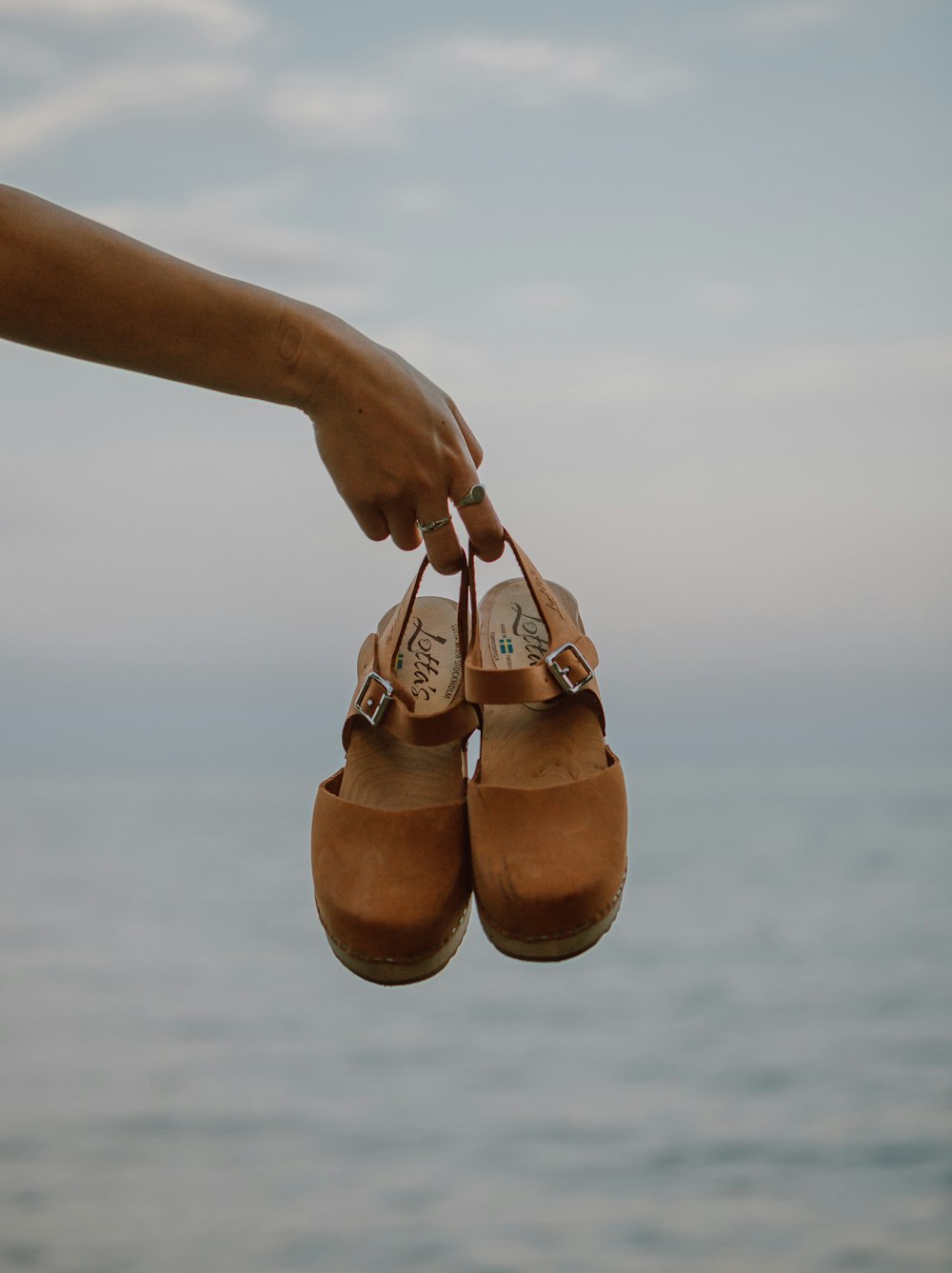 person holding brown leather shoes