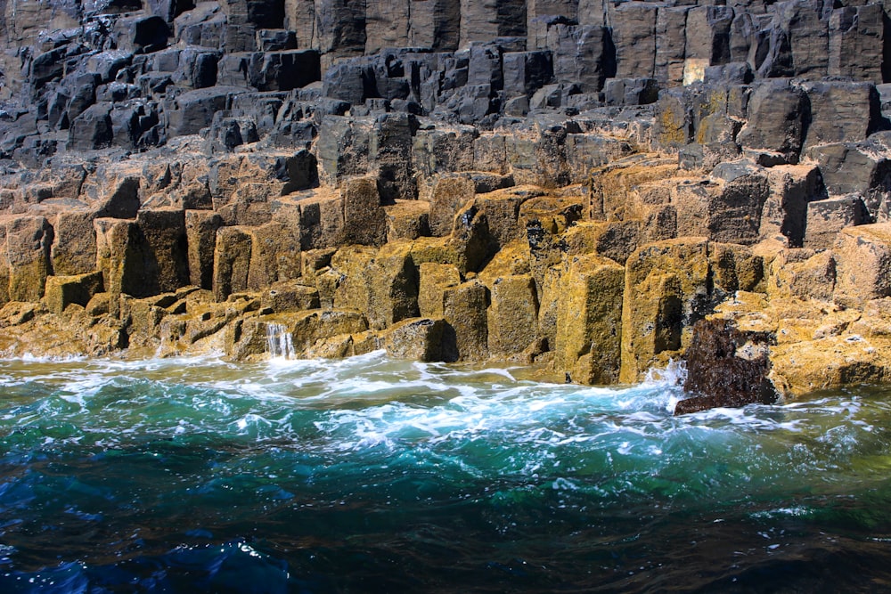 brown rock formation beside body of water during daytime