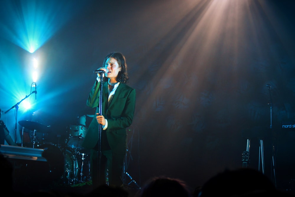 man in black suit singing on stage