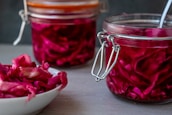 A warm kitchen scene showing jars of kimchi and sauerkraut cooling on the counter.