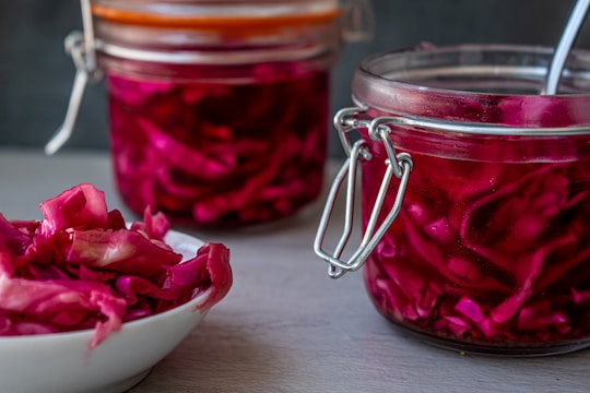 Close-up of a glass jar filled with vibrant homemade sauerkraut, bubbles rising inside.