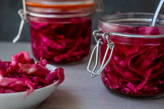 Close-up of colorful fermented vegetables in glass jars on a wooden table