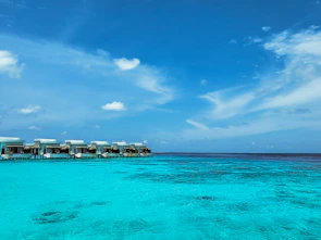 Overwater bungalow surrounded by turquoise sea under a clear blue sky.