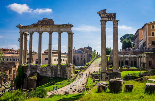 Historic Roman ruins bathed in warm afternoon light with tourists exploring.