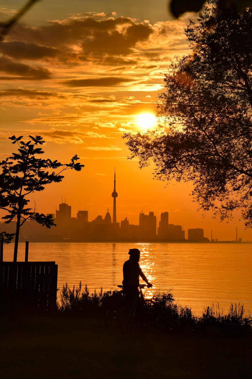 silhouette of man standing near body of water during sunset