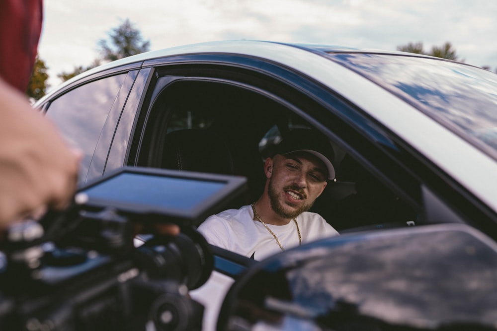 man in white shirt wearing black sunglasses sitting on car