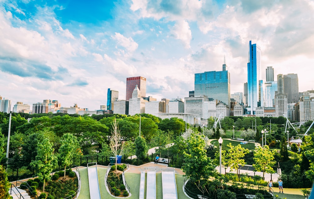 green trees near city buildings under blue sky during daytime