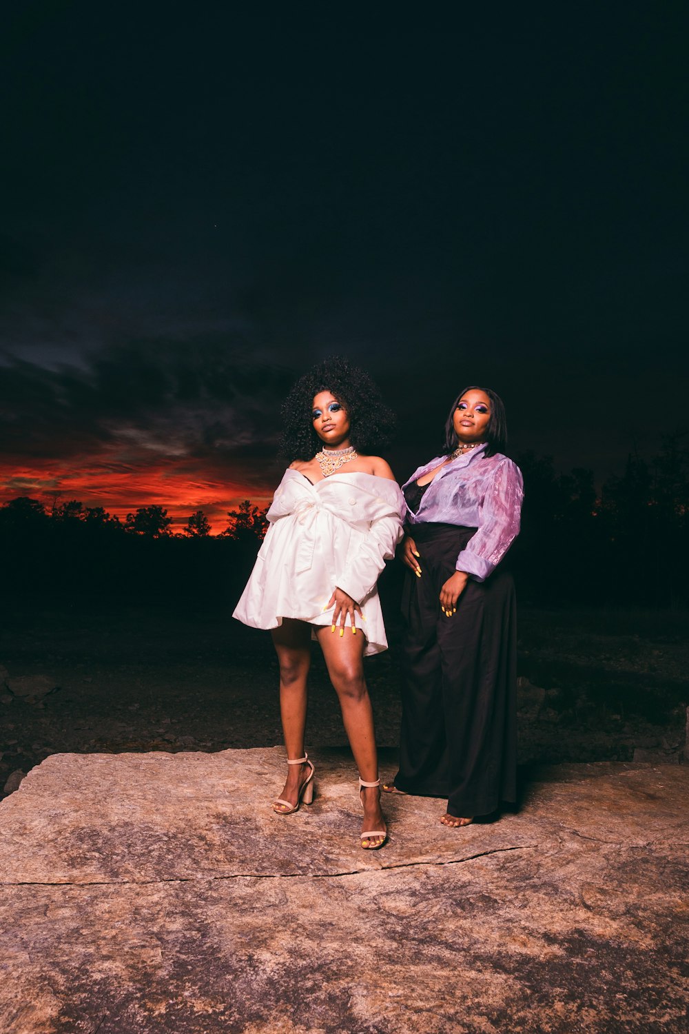 2 women standing on brown sand during night time