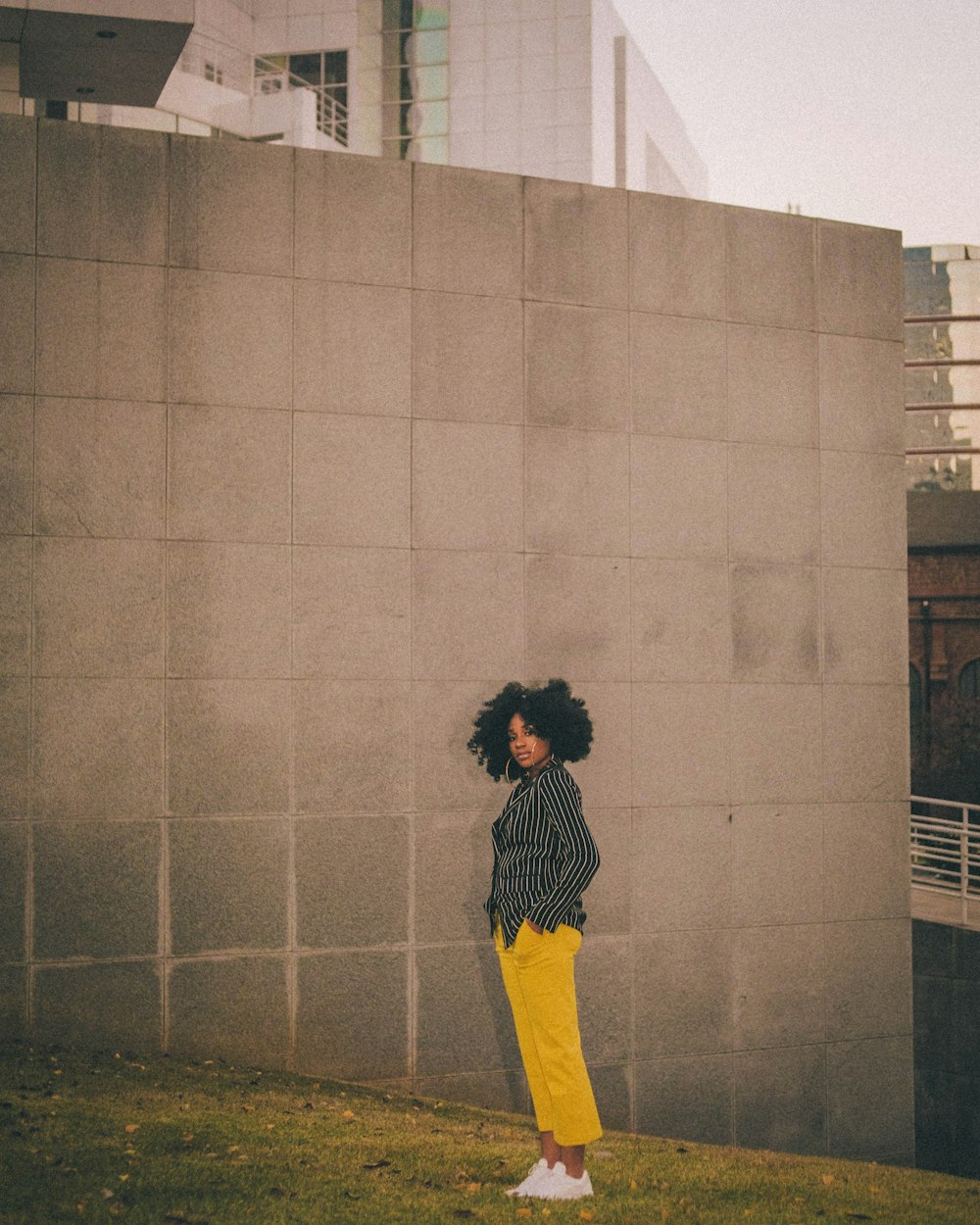 woman in yellow and black dress standing beside gray brick wall