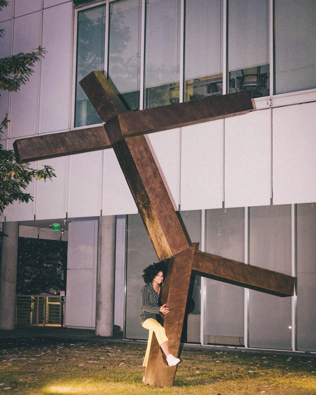 woman in black jacket and white pants sitting on brown wooden cross