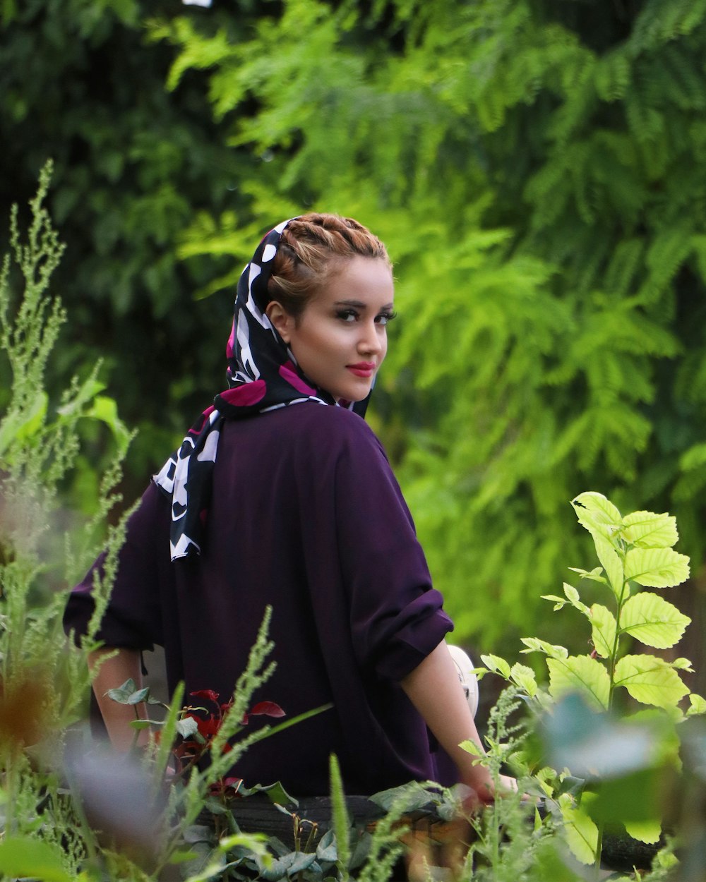 woman in black and pink hijab standing near green plants during daytime