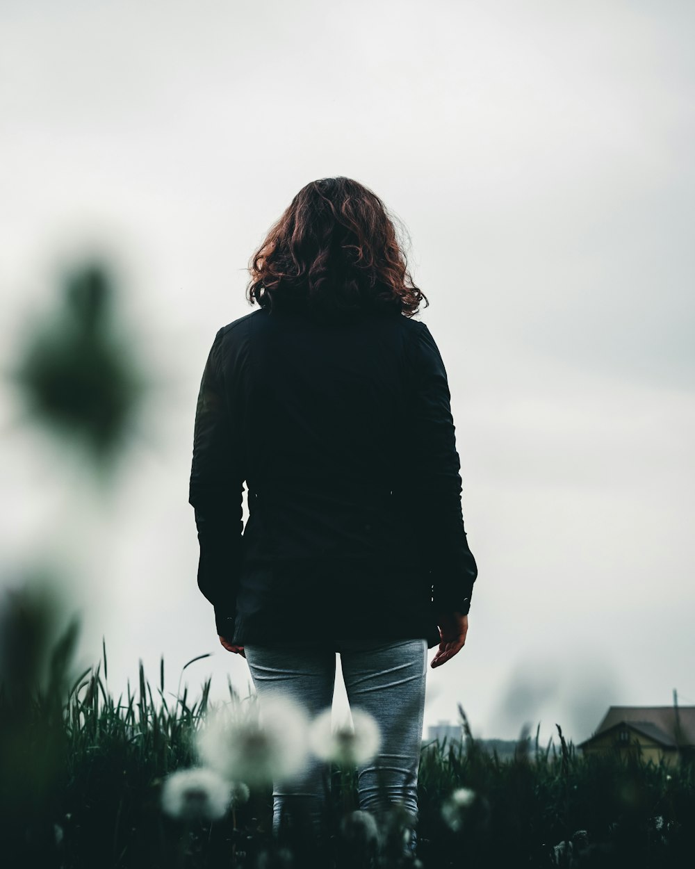 Femme en veste noire debout sur le champ d’herbe verte pendant la journée