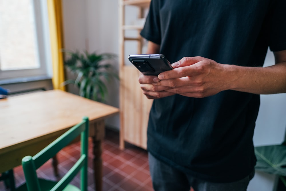 Personne en chemise bleue à manches longues tenant un smartphone noir