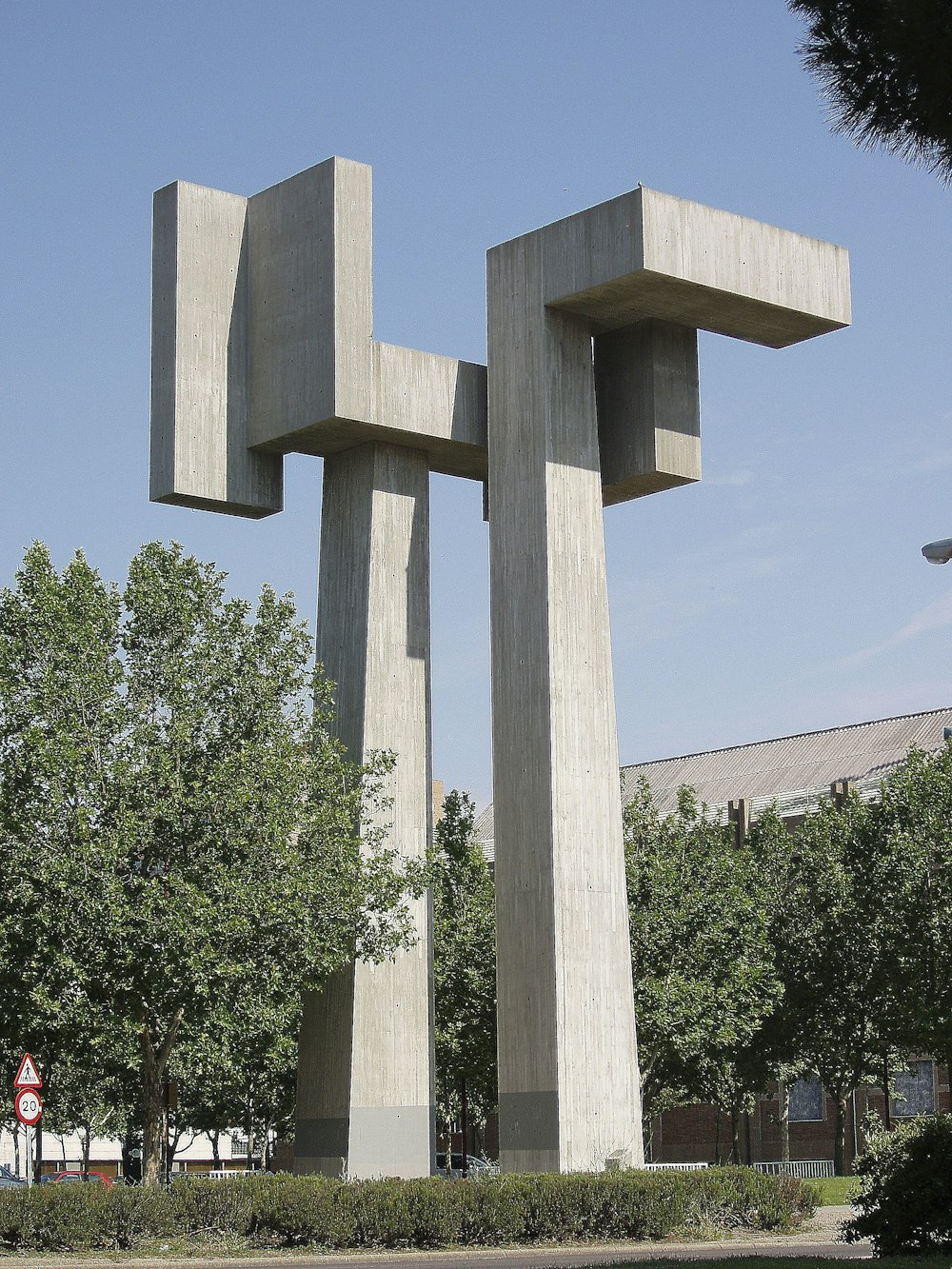 Estatua de la cruz de hormigón gris cerca de los árboles verdes durante el día