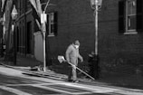 A team of workers sweeping leaves and debris from a city sidewalk.