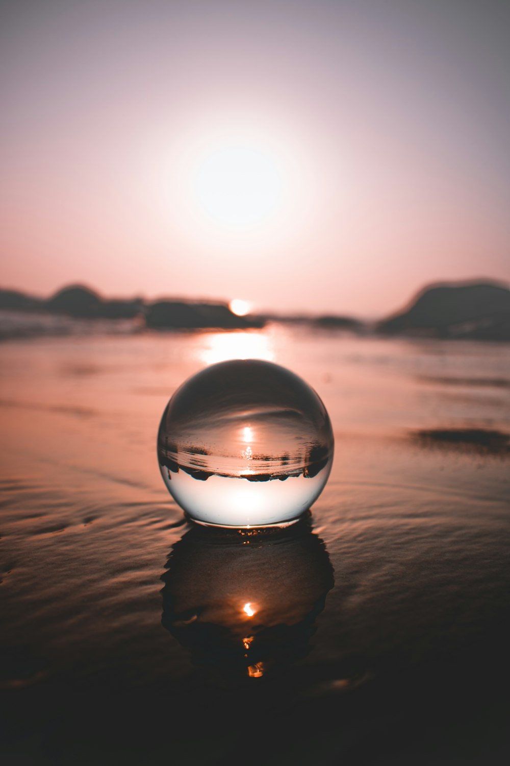 clear glass ball on brown sand during daytime