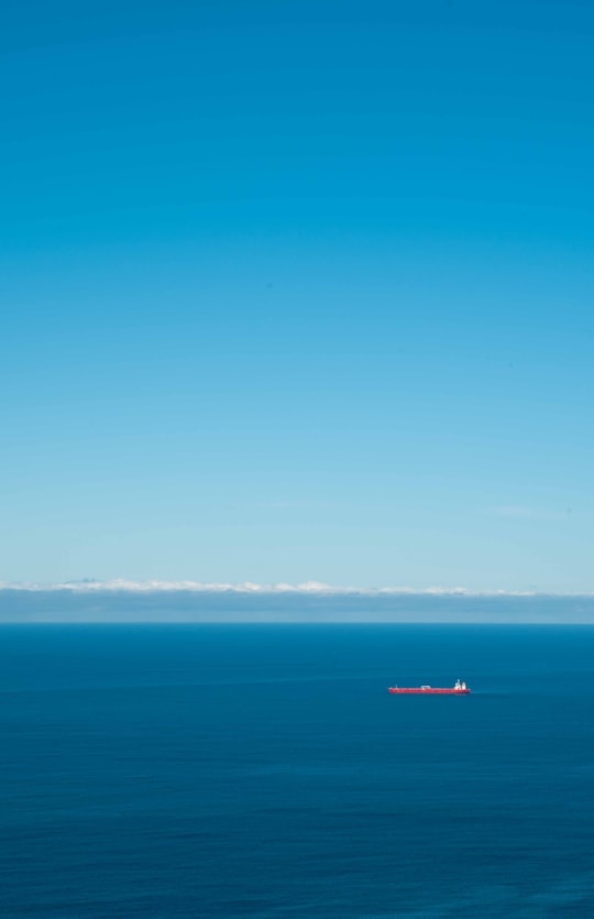 red boat on sea under blue sky during daytime in Stanwell Tops NSW Australia