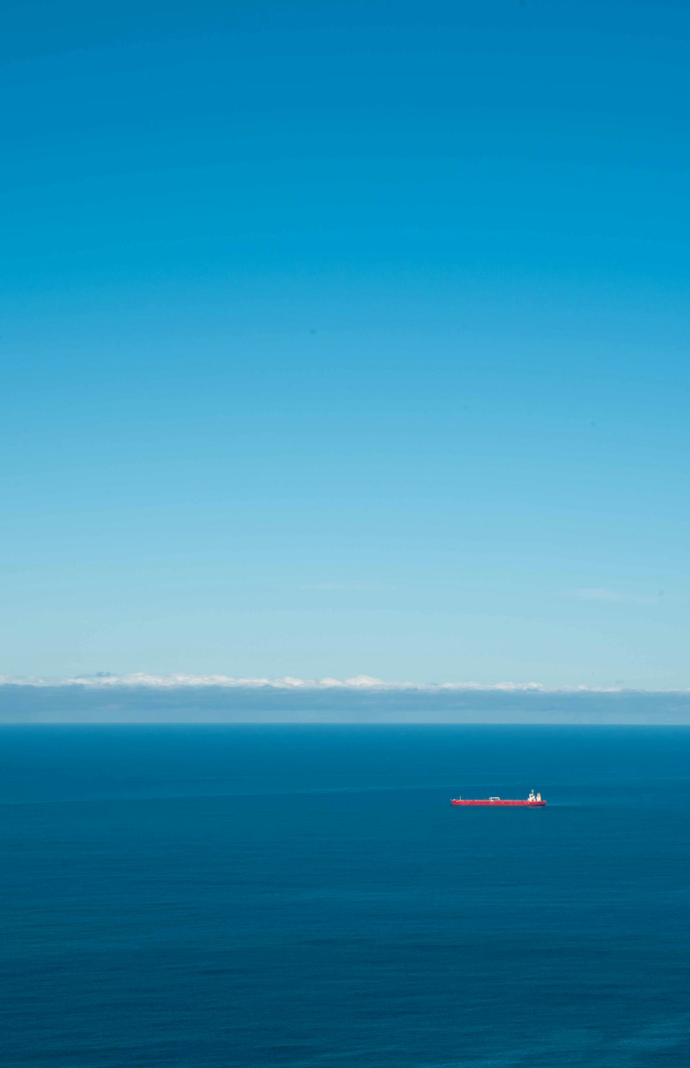 red boat on sea under blue sky during daytime