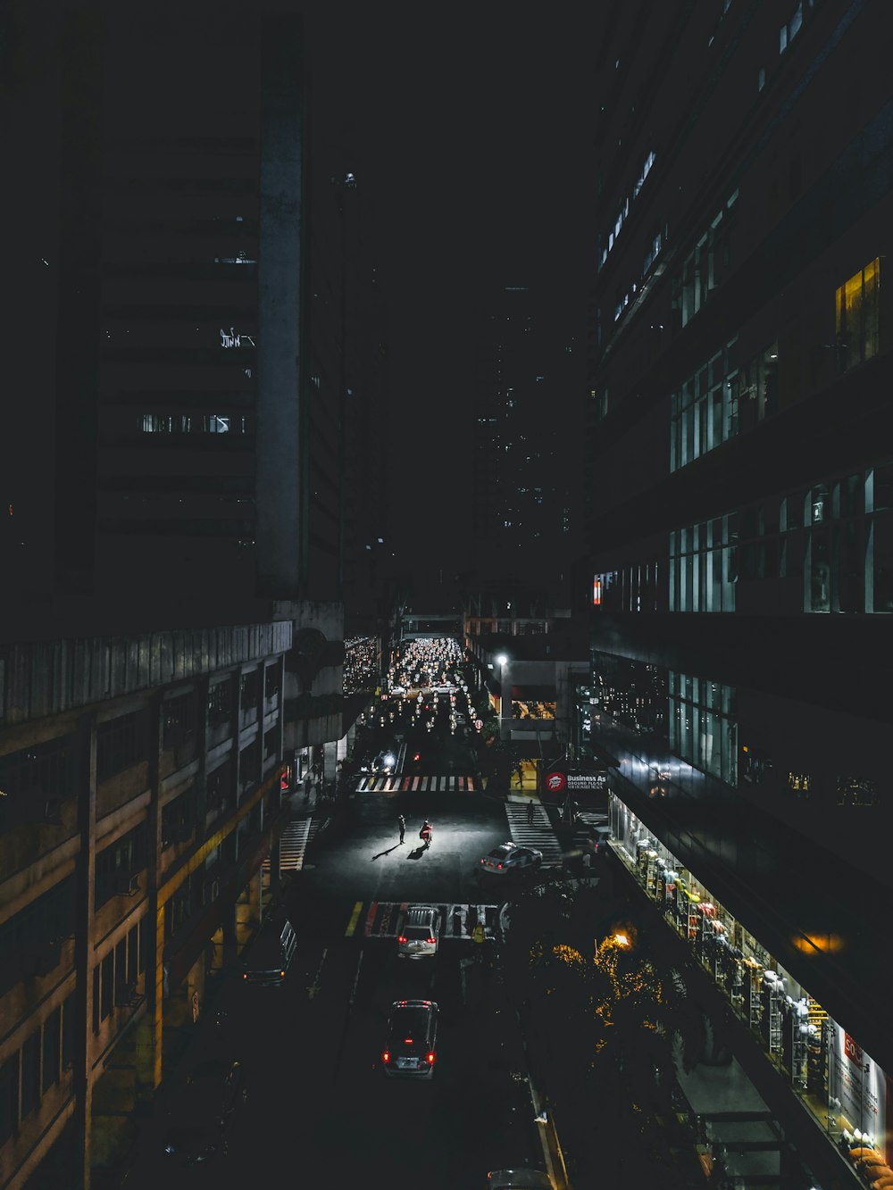 cars on road in between high rise buildings during night time