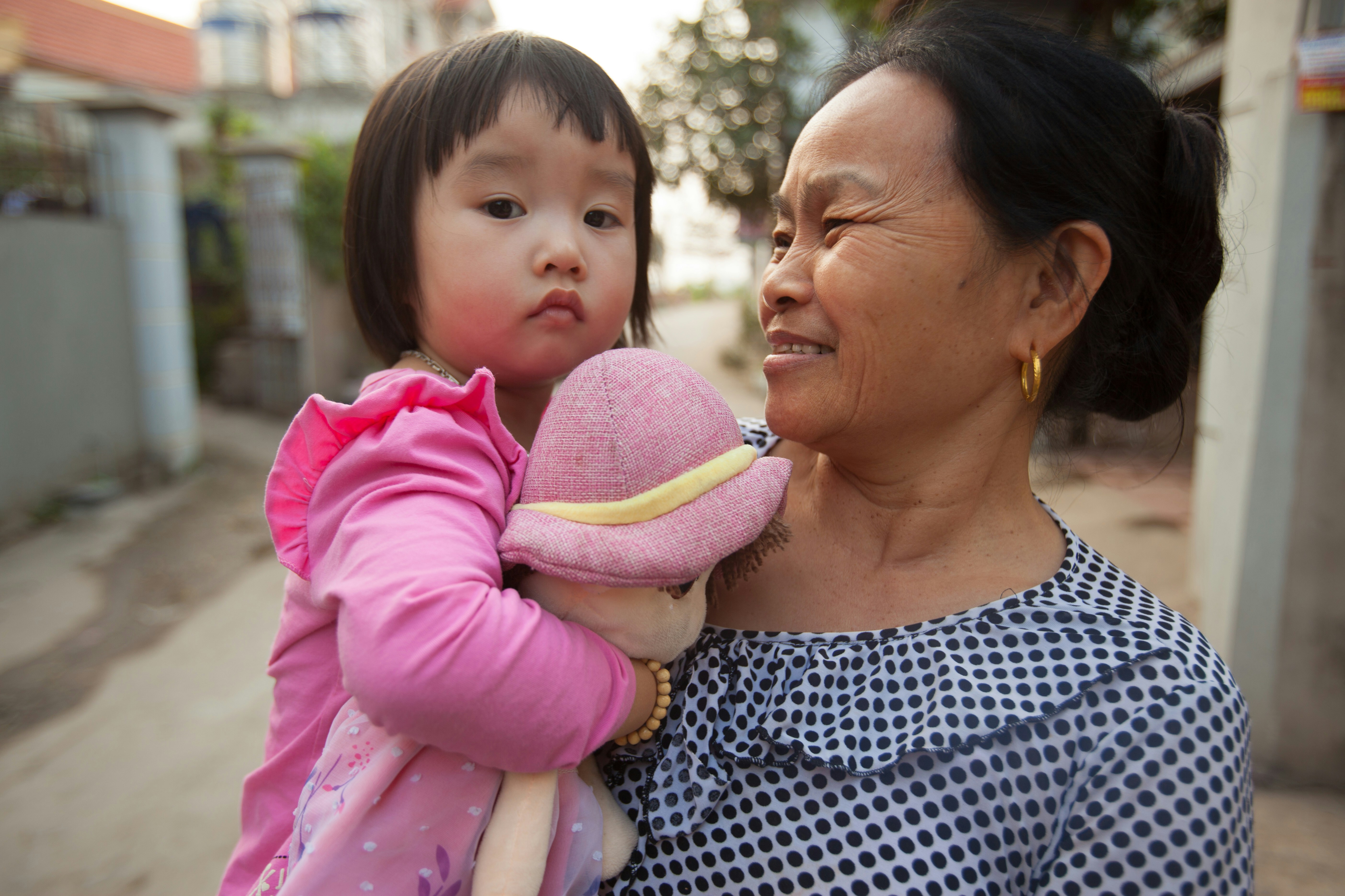 woman in black and white shirt carrying baby in pink and white long sleeve shirt