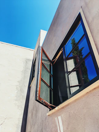 Close-up of gleaming clean windows reflecting a sunny sky on a tan-colored home.