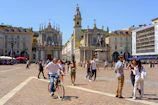 A lively European city square filled with outdoor cafes and people enjoying a sunny afternoon.