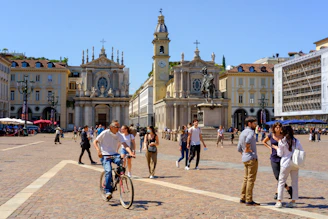 A lively city square in Brașov filled with locals and tourists enjoying a sunny day.