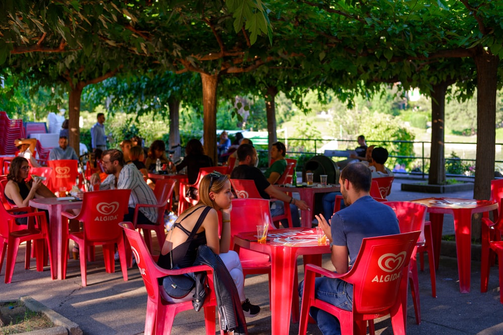 people sitting on red plastic chairs during daytime