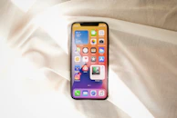 Close-up of a smartphone displaying colorful apps against a soft fabric background.