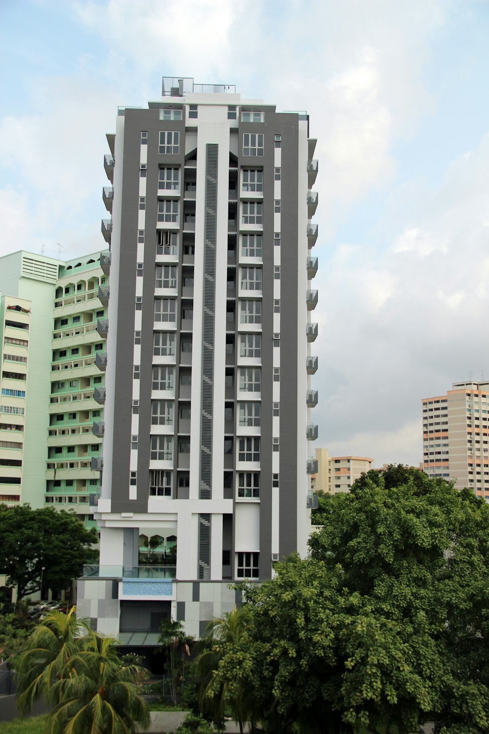 edificio in cemento bianco vicino agli alberi verdi sotto il cielo blu durante il giorno