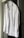 A neatly ironed white dress shirt hangs on a hanger against a neutral background. The shirt is buttoned up with long sleeves, a collar, and a front pocket.