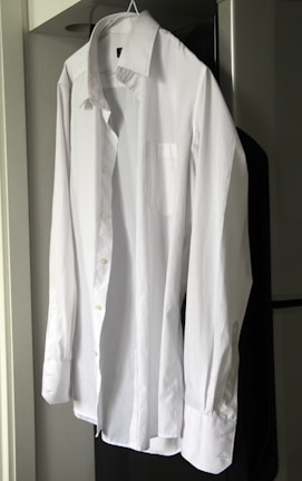 A crisp white shirt freshly pressed and hanging on a wooden hanger.