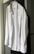 A neatly ironed white dress shirt hangs on a hanger against a neutral background. The shirt is buttoned up with long sleeves, a collar, and a front pocket.