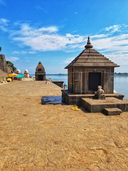 brown wooden house near body of water during daytime in Maheshwar India