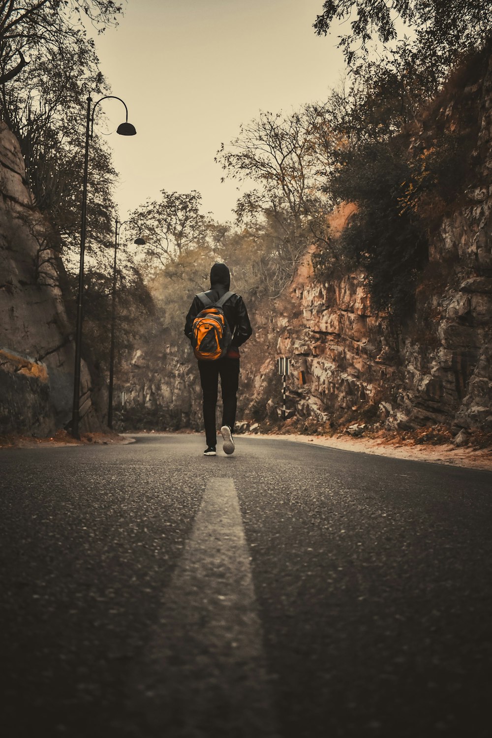 uomo in giacca nera e pantaloni neri che camminano sulla strada durante il giorno