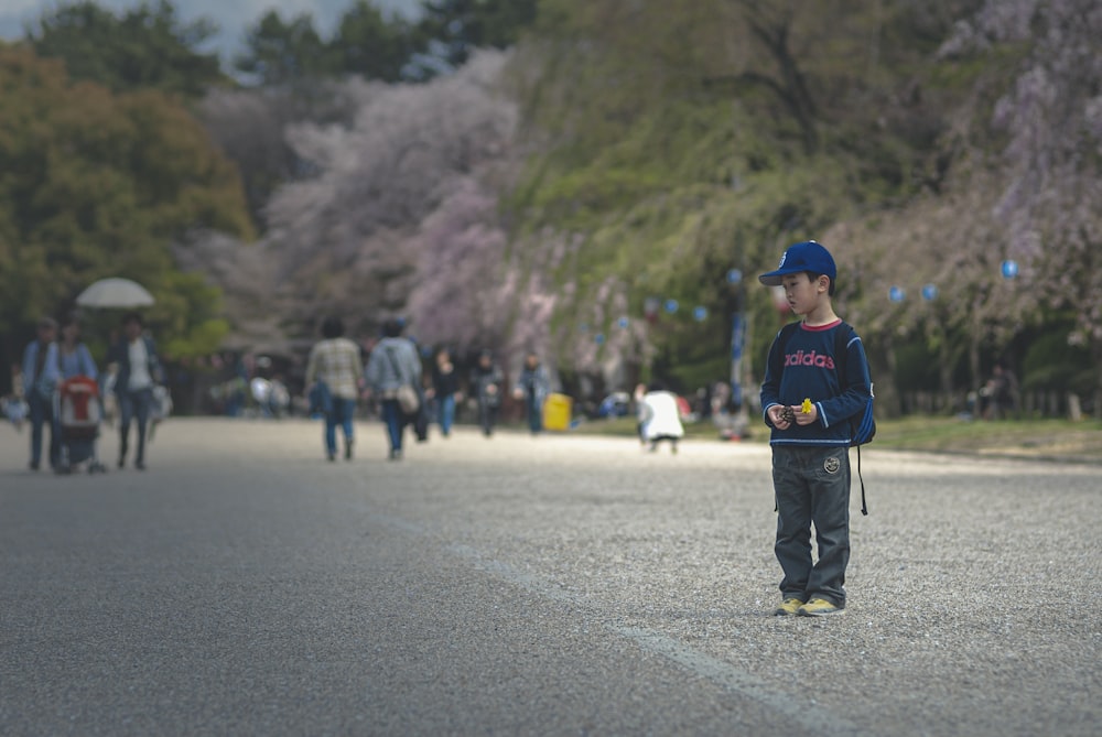 man in blue jacket walking on road during daytime