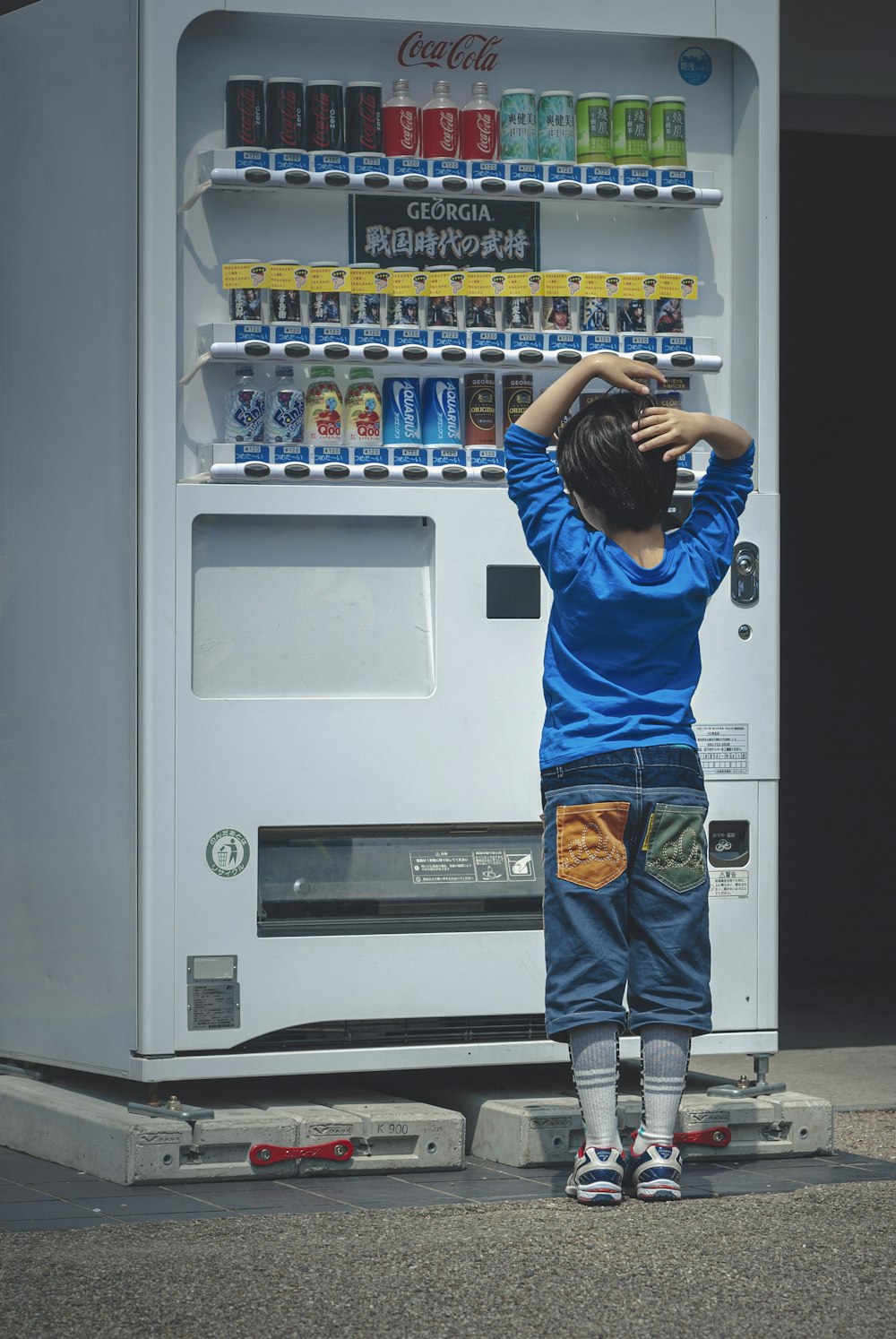 um menino em pé na frente de uma máquina de venda automática