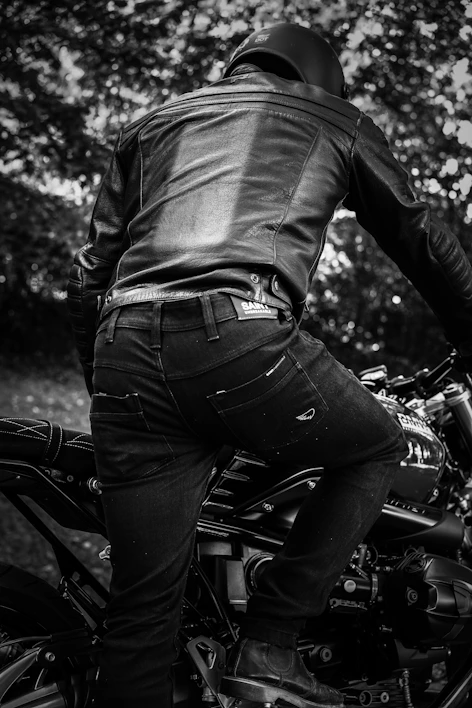 Close-up of a rugged leather motorcycle jacket draped over a vintage bike seat.