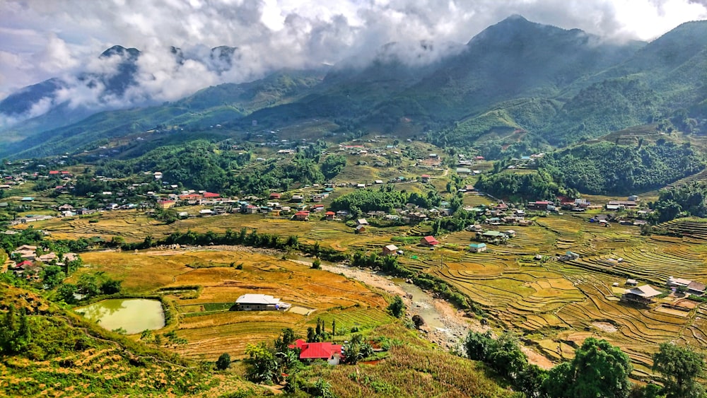 green grass field near mountain under white clouds during daytime