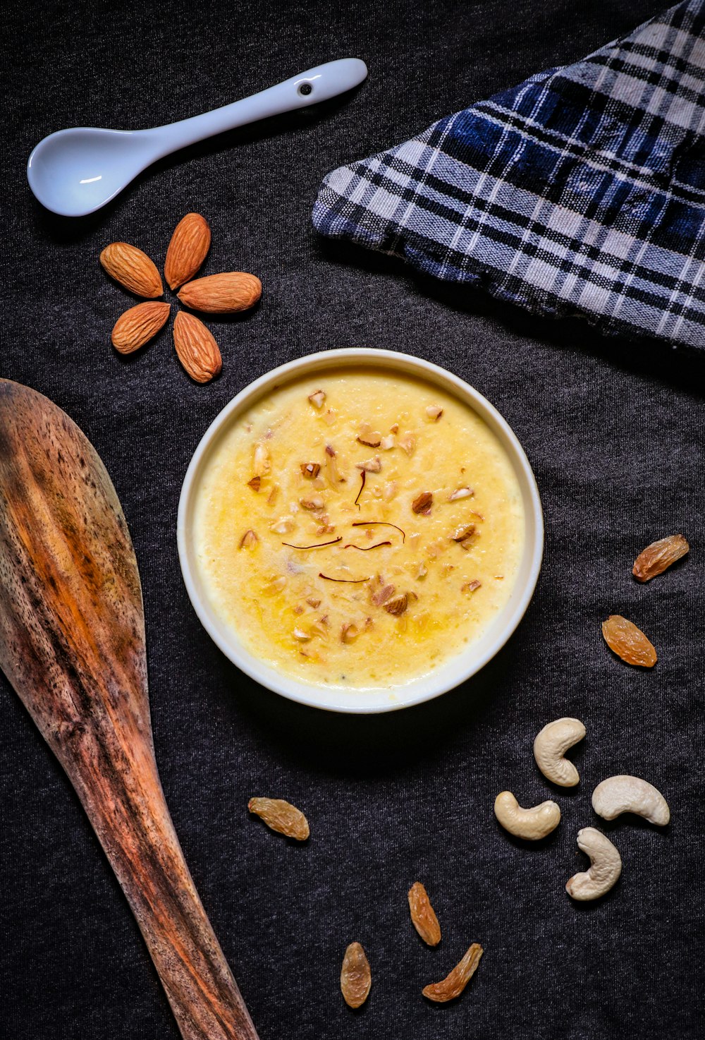 white ceramic bowl with soup beside brown wooden spoon