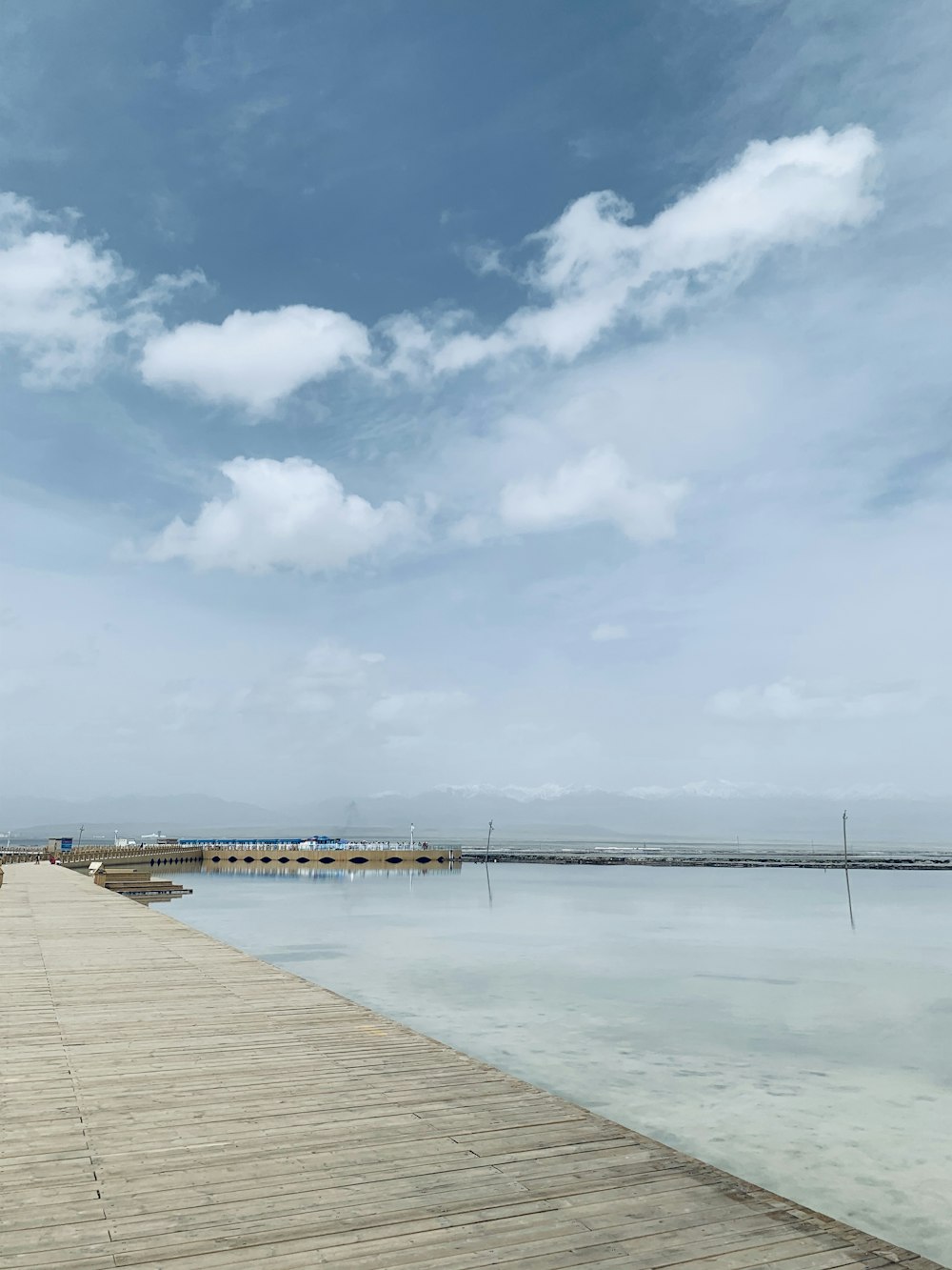 brown wooden dock on sea under blue sky and white clouds during daytime