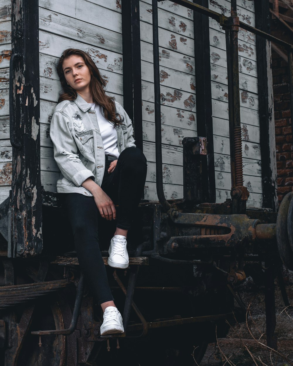 woman in white jacket and black pants standing beside black metal wheel