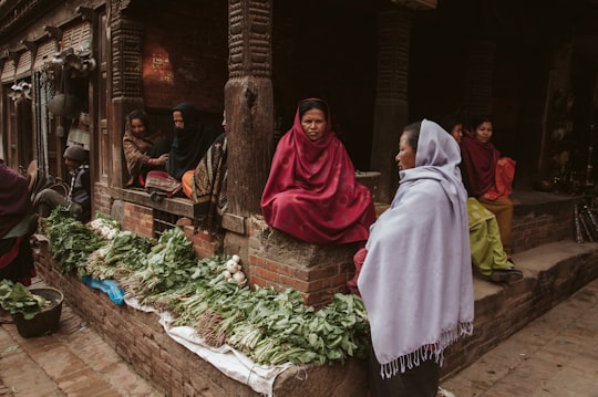 woman in red hijab sitting on brown wooden bench in Bhaktapur Nepal