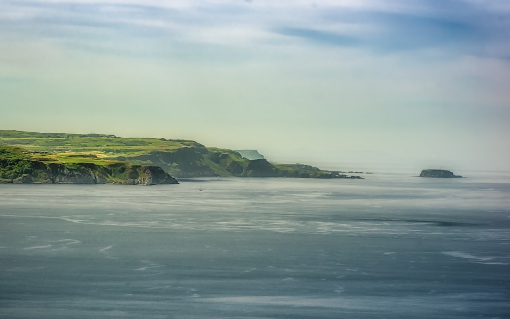 green mountain beside body of water during daytime