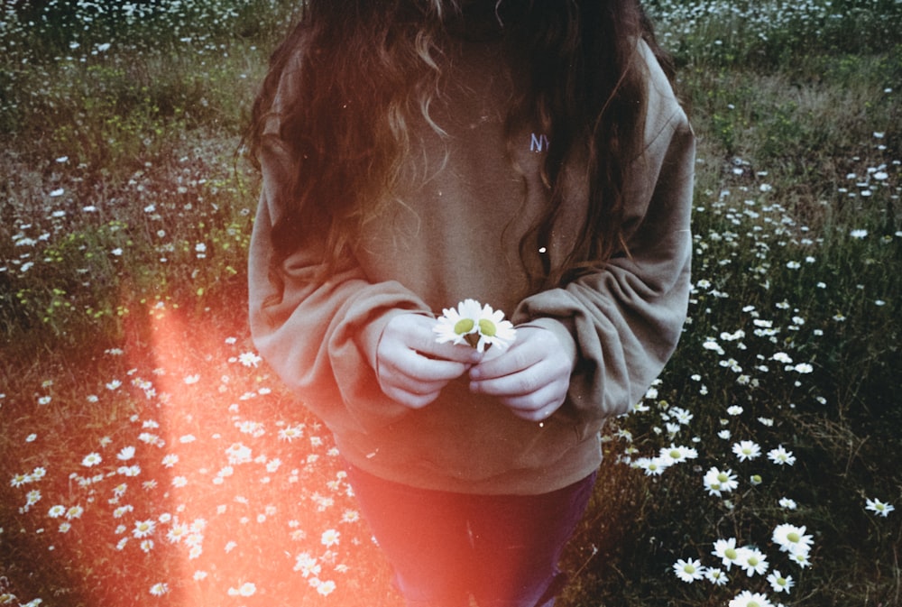 woman in green hoodie holding white flower