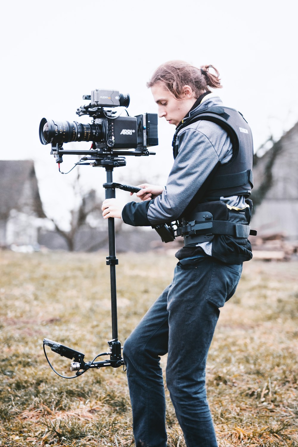 man in black jacket and blue denim jeans holding black dslr camera