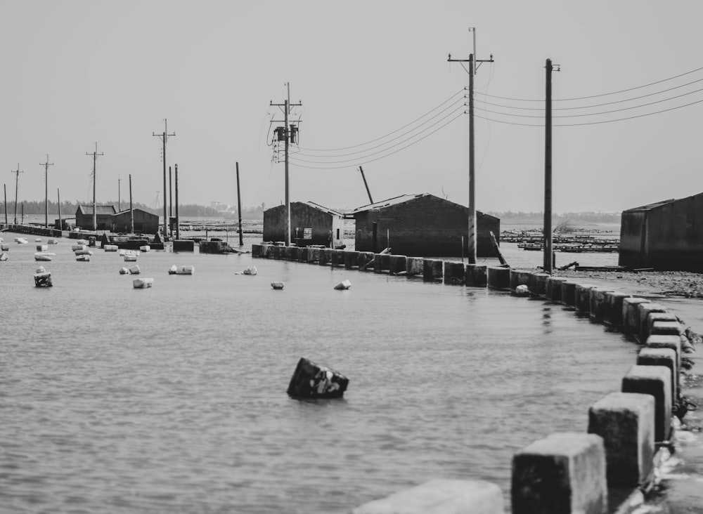 grayscale photo of people on beach near bridge