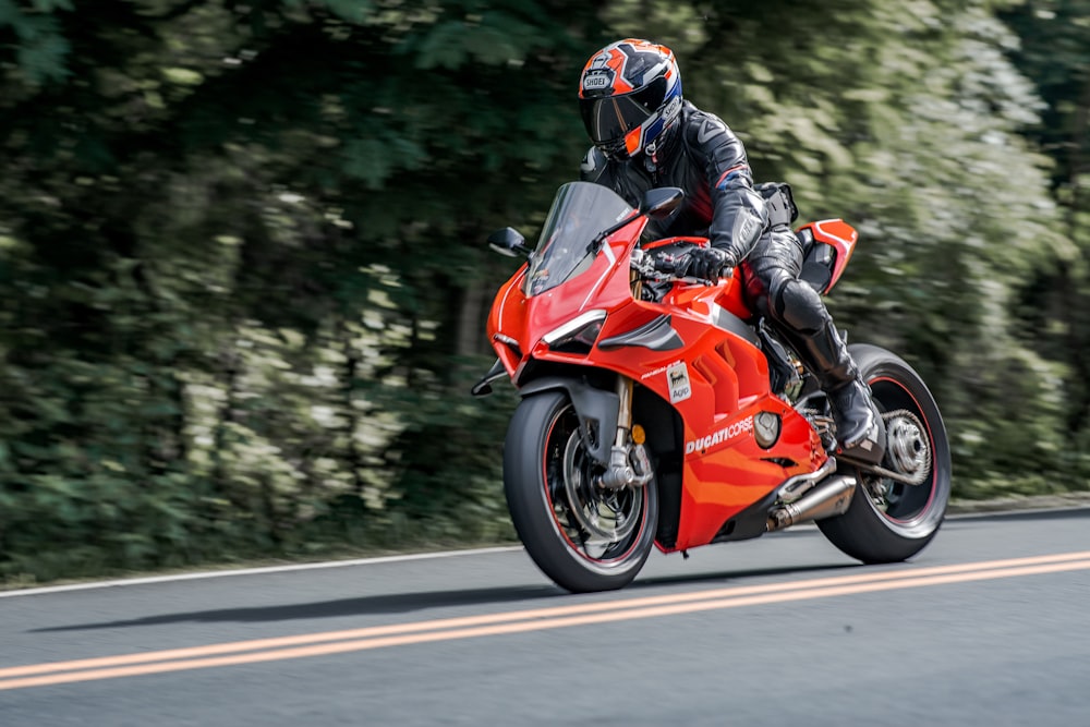 man in orange and black motorcycle suit riding on orange sports bike