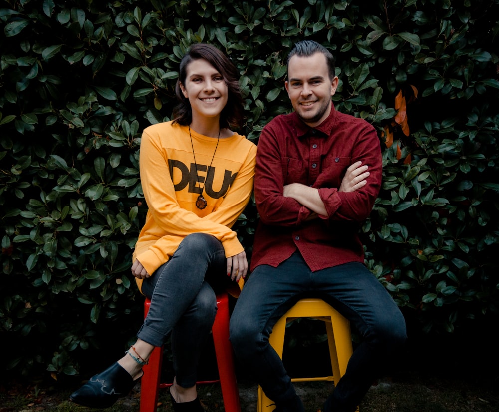 woman in yellow and black hoodie sitting beside boy in red hoodie